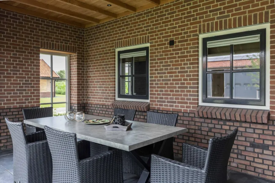 Overdekt terras met betonnen eettafel voor zes personen