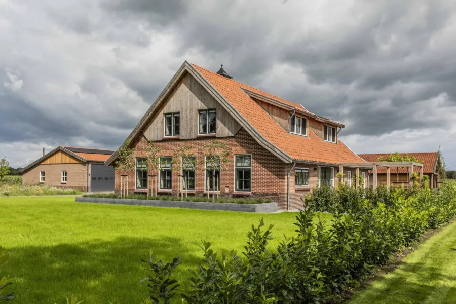 Zijgevel van de gerestaureerde boerderij met grote glaspui