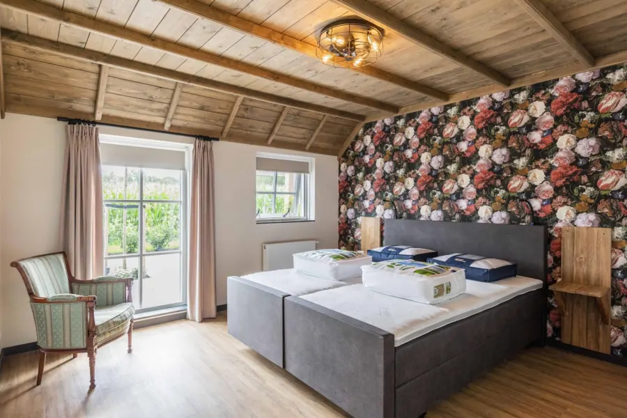 Tweede slaapkamer met houten balkenplafond en uitzicht op de tuin