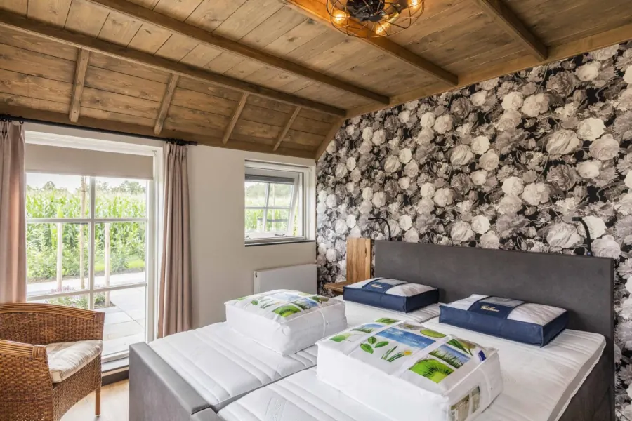 Slaapkamer met zwart-wit bloemenbehang en openslaande deuren