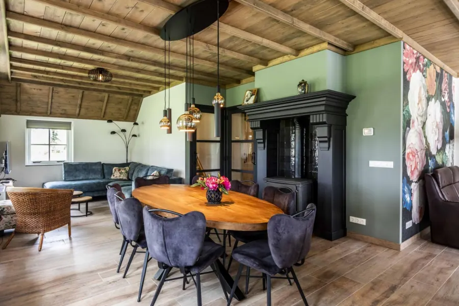 Woonkamer met ronde eettafel, zithoek en zwarte schouw