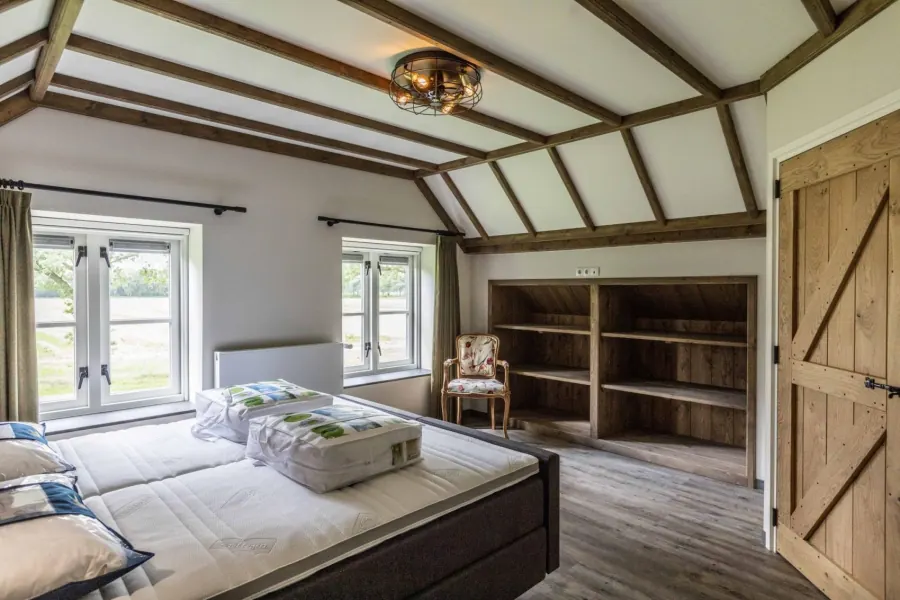 Slaapkamer met openslaande deuren naar de tuin en houten kastenwand
