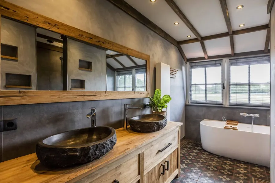 Badkamer met dubbele wastafel, vrijstaand bad en uitzicht op het weiland